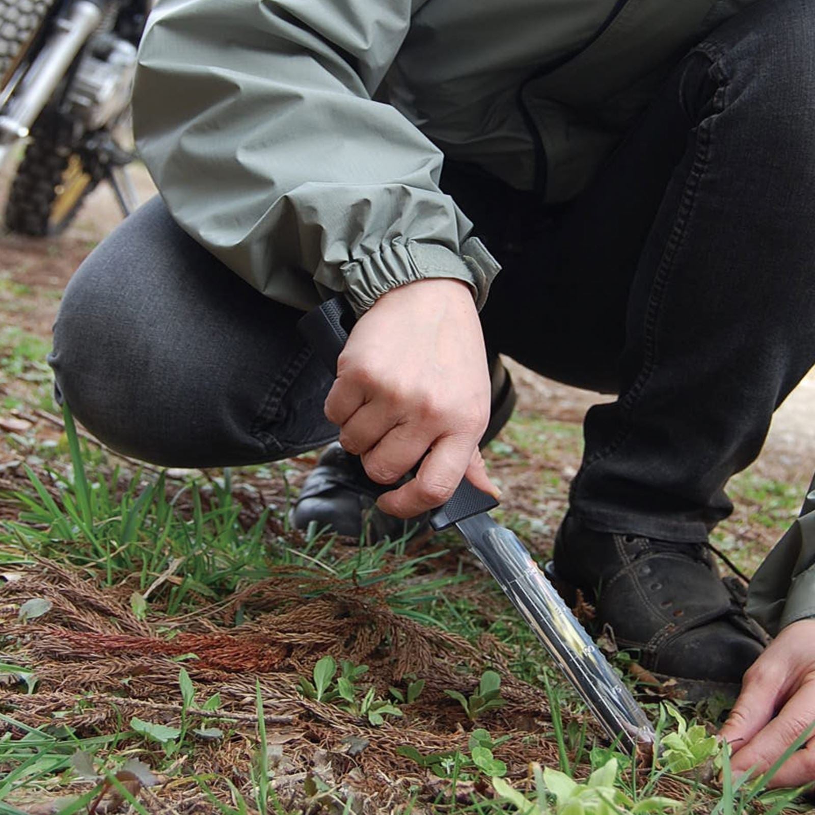 Person using the Nisaku Yamagatana 7.5-inch Japanese Stainless Steel Knife to take a weed out of the ground.