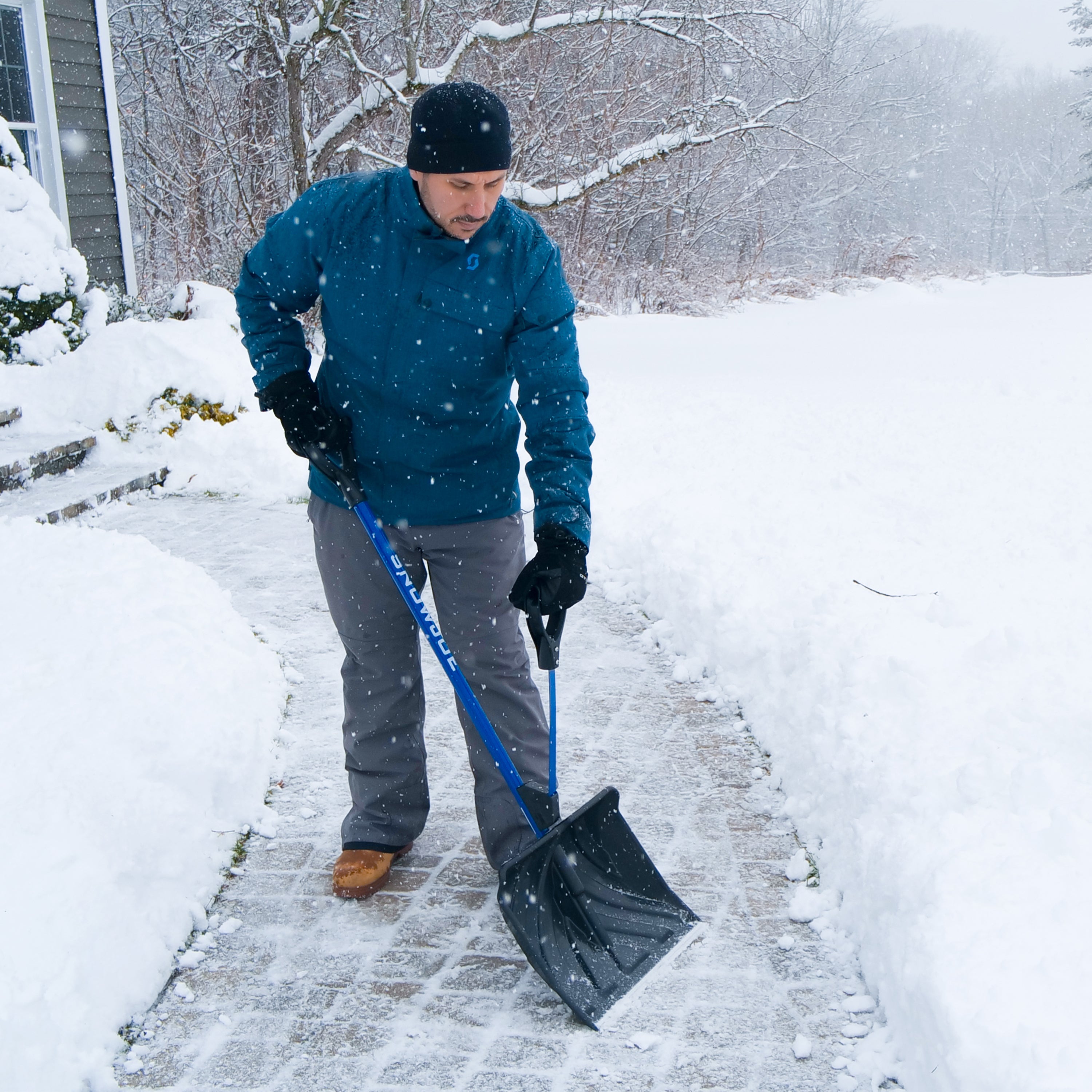 man shovelling snow off walkway with snow joe strain reducing shovel